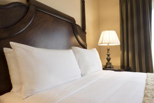 a bedroom with a bed with white pillows and a lamp at Ayres Suites Ontario at the Mills Mall - Rancho Cucamonga in Ontario