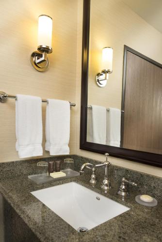 a bathroom with a sink and a mirror and towels at Ayres Suites Ontario at the Mills Mall - Rancho Cucamonga in Ontario