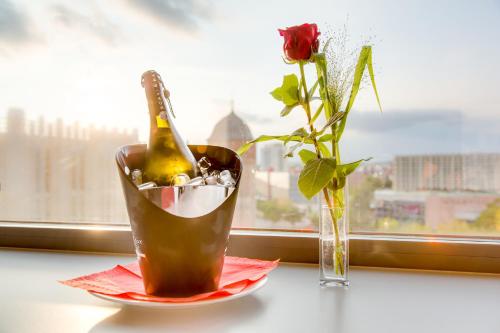 a bottle of champagne and a vase with a flower at Biendo Hotel in Chemnitz