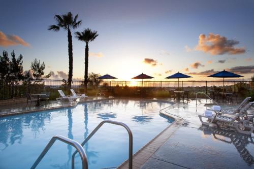 una gran piscina con sillas y sombrillas en Ayres Suites Mission Viejo - Lake Forest, en Mission Viejo