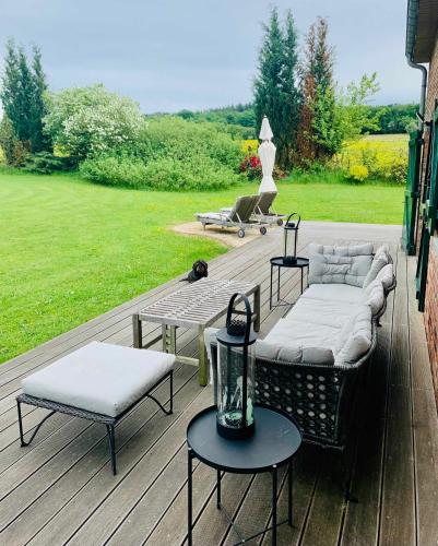 a wooden deck with couches and tables on it at Lovely Meadow House in the land of Croix Scaille in Gedinne
