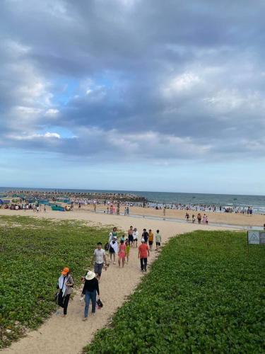 a group of people walking on a sandy beach at Comfortable Family Apartment at Sealinks Mui Ne in Ấp Ngọc Hải
