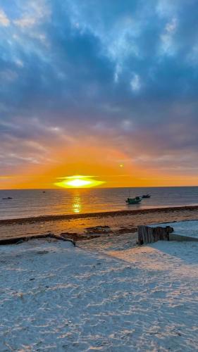 a sunset on the beach with a boat in the water at Restaurante & Pousada Portal dos Ventos in Icapuí