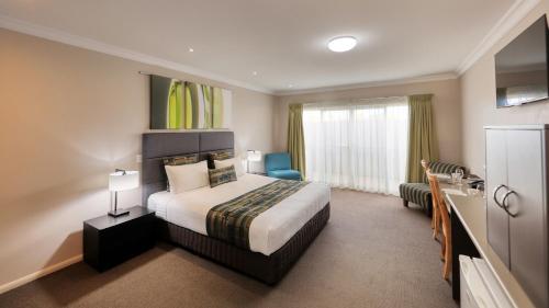 Habitación de hotel con cama grande y baño. en Drovers Motor Inn en Dalby
