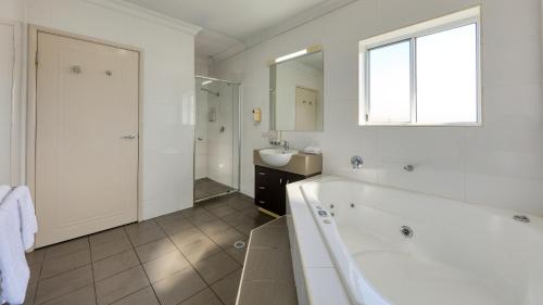 a bathroom with a tub, sink, and mirror at Drovers Motor Inn in Dalby