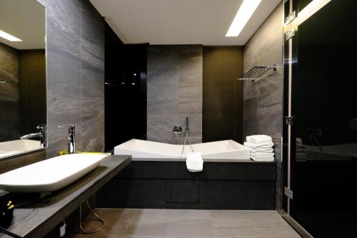 bagno con vasca e lavandino di Tongzhan Design Inns ad Anping