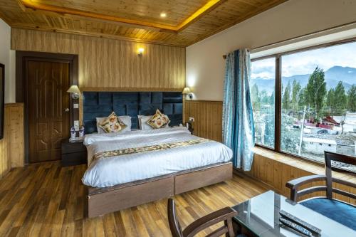 a bedroom with a large bed and a large window at HOTEL CHANTSA in Leh