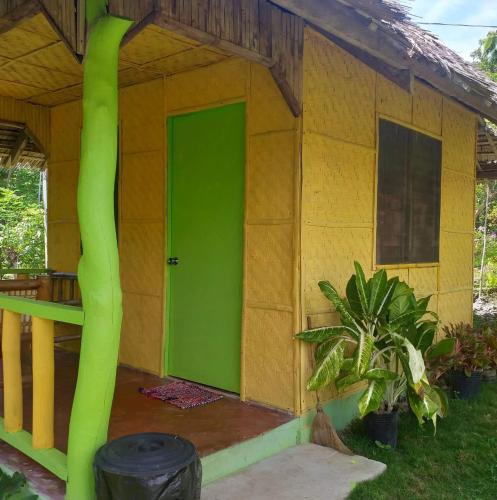 a green door in a small house with a plant at La Villa Alta in Siquijor