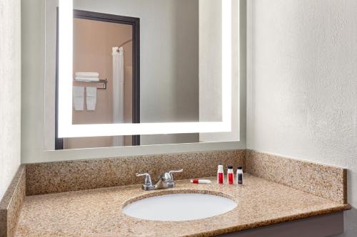 a bathroom with a sink and a mirror at Days Inn by Wyndham Kansas City International Airport in Kansas City