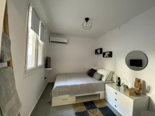 Habitación blanca con cama y espejo en Tiny Little House en Athens