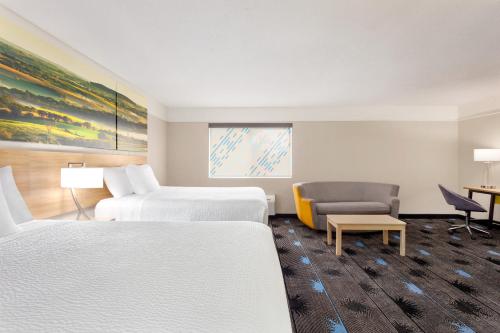 a hotel room with two beds and a chair at Days Inn by Wyndham Kansas City International Airport in Kansas City