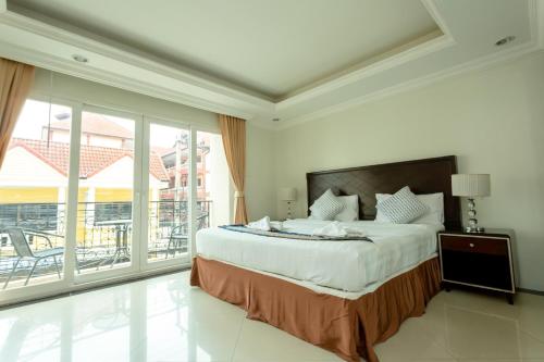 a bedroom with a large bed and a balcony at Ivory Palace Hotel in Pattaya Central