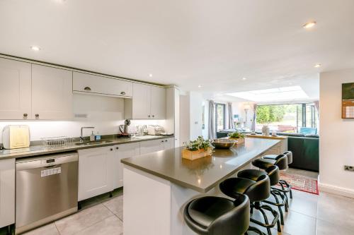 a kitchen with white cabinets and a large island with bar chairs at Carr House Farm in Glossop