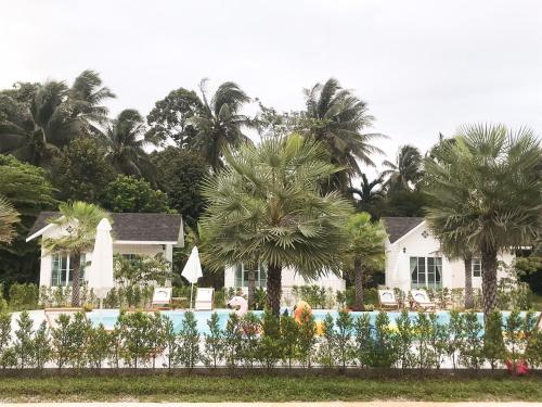 a house with palm trees and a swimming pool at Thirty Tree Garden House in Chumphon