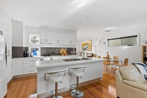 a kitchen with white cabinets and a kitchen island with bar stools at The Lake House in Ocean Grove