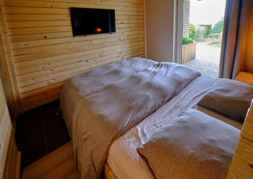 two beds in a room with a tv on a wall at La tanière in Chaudfontaine