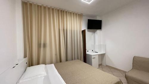 a bedroom with a bed and a window with a television at Hotel Boschetto in Follonica