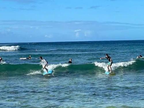 a group of people riding waves on surfboards in the ocean at Quiet Kiahuna plantation , New Remodel with AC in Koloa