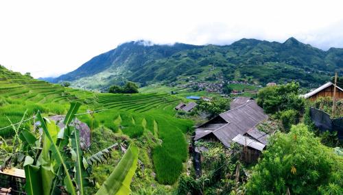 a village on a hillside with mountains in the background at Surelee Homestay in Sa Pa