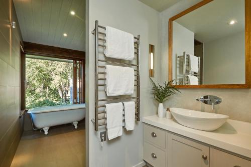 a bathroom with a tub and a sink and a mirror at Kanuka Terrace - Luxury Strawbale House in Kaikoura