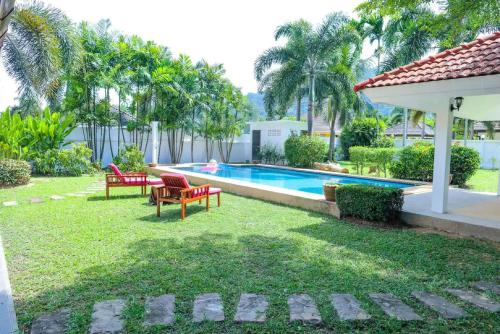 um quintal com uma piscina, uma mesa e cadeiras em Garden Villa Paklok em Ban Bang Rong