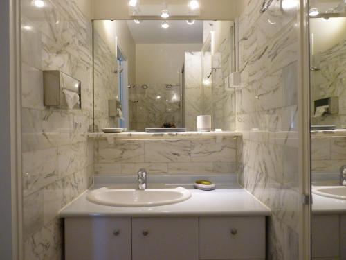 W białej łazience znajduje się umywalka i lustro. w obiekcie Sol-y-Days Eden, Magnifique appartement de deux chambres, en duplex face a la mer et au port de plaisance w mieście La Grande-Motte