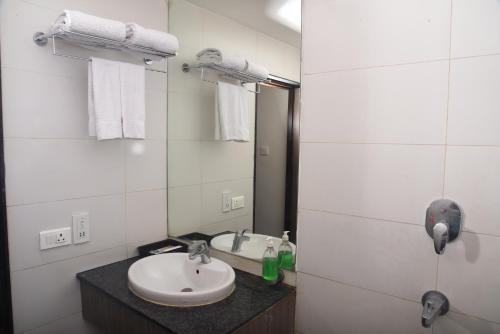 a white bathroom with a sink and a mirror at Hotel Sabareesh Park in Madurai