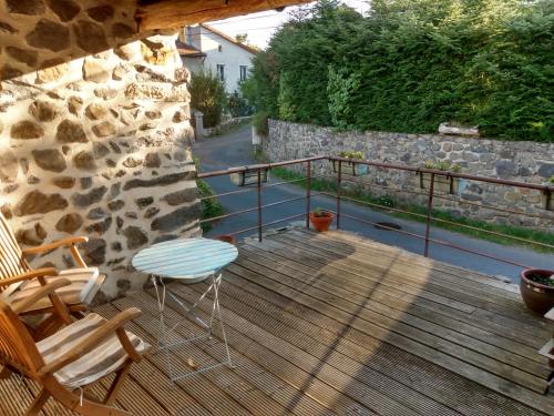 a wooden deck with two chairs and a stone wall at Studio 45m2, à la campagne, à 15 mns du Puy en Velay in Lantriac