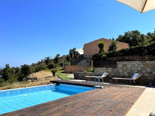 a swimming pool with a wooden deck next to a house at B&B Le Ginestre in Cefalù