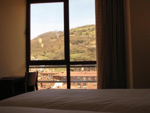 a bedroom with a large window with a mountain view at Hotel Ruta de la Plata de Asturias in Pola de Lena
