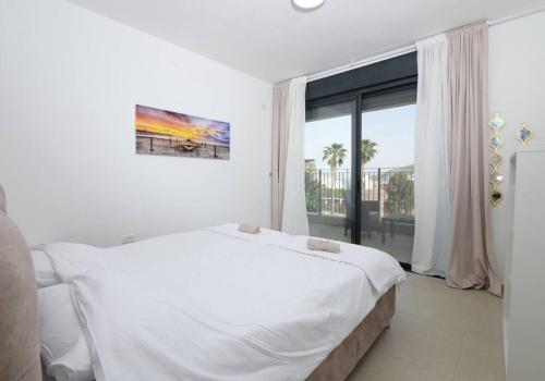 1 dormitorio blanco con 1 cama grande y ventana grande en אצולת הים - טבריה en Tiberias