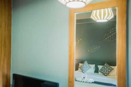 a mirror in a room with a bed with pillows at The Rubber Hotel Phuket in Thalang