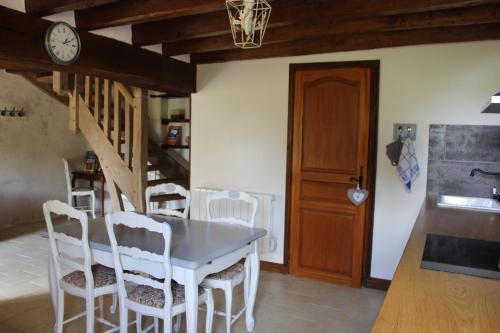 a dining room with a table and chairs and a clock at Gîtes à l'ombre des chênes in Châteauvieux