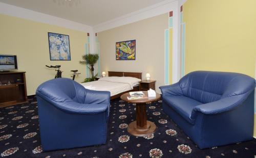 a hotel room with two blue chairs and a bed at Brioni Suites in Ostrava