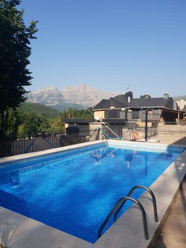 a large blue swimming pool with mountains in the background at Mandilar Confort Panticosa in Panticosa