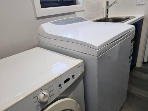 a small kitchen with a washing machine and a sink at Spacious Modern Apartment - St Kilda East in Melbourne