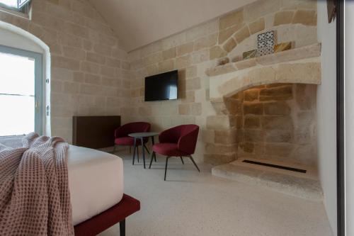 a room with a stone fireplace with chairs and a table at PIANELLE RESORT in Matera