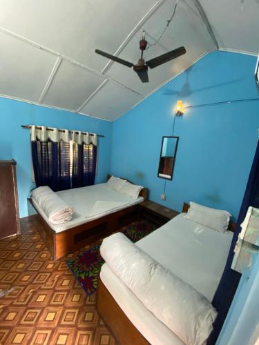 Habitación con 2 camas y ventilador de techo. en Nature Safari Camp en Chitwan