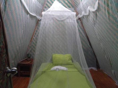 a small tent with a green bed in it at SHUKRAN Apartelle in Siquijor