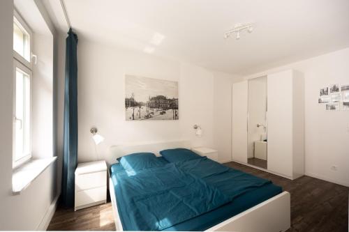 L.E. Home في لايبزيغ: غرفة نوم بيضاء بسرير ازرق ونافذة