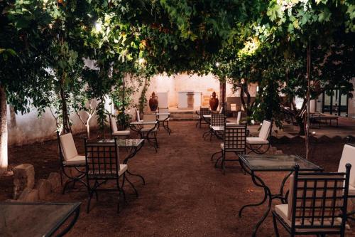 a group of tables and chairs under trees at Tenuta Tresca Suites - Dimora Storica in San Cassiano