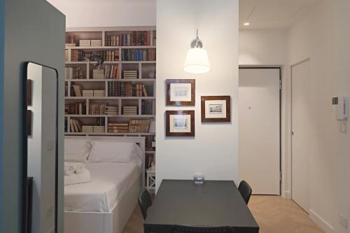 Schlafzimmer mit einem Bett, einem Tisch und Bücherregalen in der Unterkunft OreaSpiti - Not Only a Suite in Magenta Quarter in Mailand