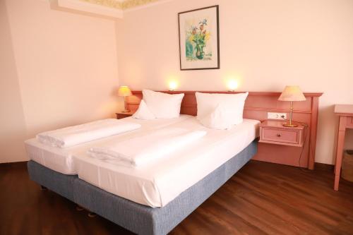ein Schlafzimmer mit einem großen Bett mit weißer Bettwäsche in der Unterkunft Parkhotel Altmühltal in Gunzenhausen