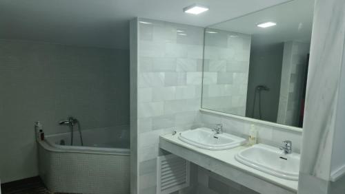 uma casa de banho com 2 lavatórios, uma banheira e um espelho. em TRIPLEX DE LUJO EN MOJACAR em Mojácar