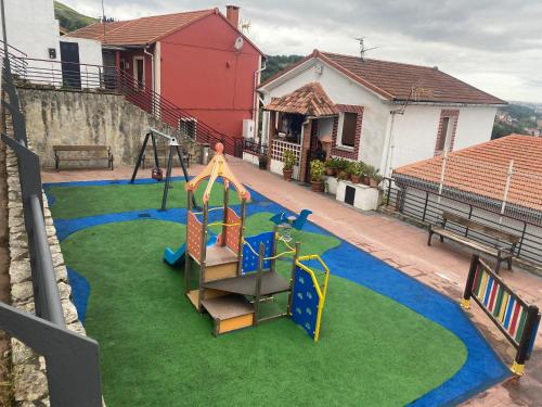a playground in a yard with a slide and swings at Caramelo in Bilbao