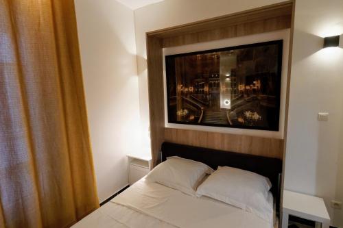 une chambre avec un lit avec un tableau sur le mur dans l'établissement Paris Opéra / Galeries Lafayette : charmant studio, à Paris