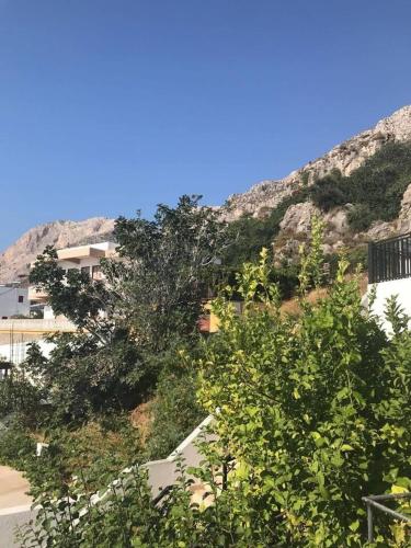 a building with a mountain in the background with trees at poets apertment in armeos masouri in Masouri