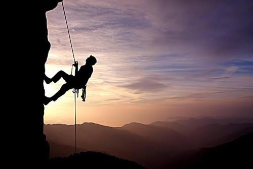 a man hanging from a rope while climbing a cliff at poets apertment in armeos masouri in Masouri