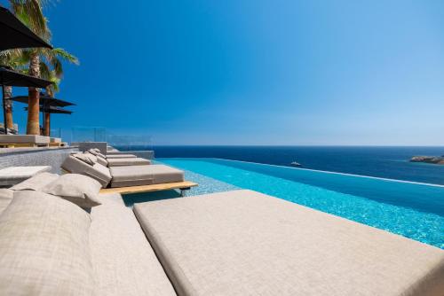 a swimming pool with lounge chairs and the ocean at Tropicana Hotel , Suites & Villas Mykonos in Paradise Beach