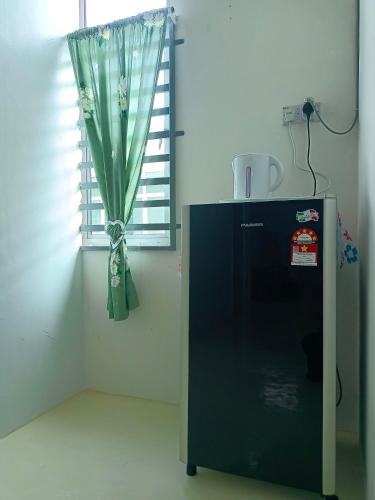 a black refrigerator in a room with a window at Homestay Muslim in Kuala Ketil